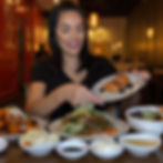 Nina Unrated holding a small plate of appetizers at a restaurant.
