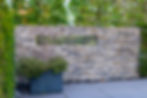 Modern stone wall with architectural opening integrated into landscape design through hardscape services on Martha’s Vineyard and Cape Cod