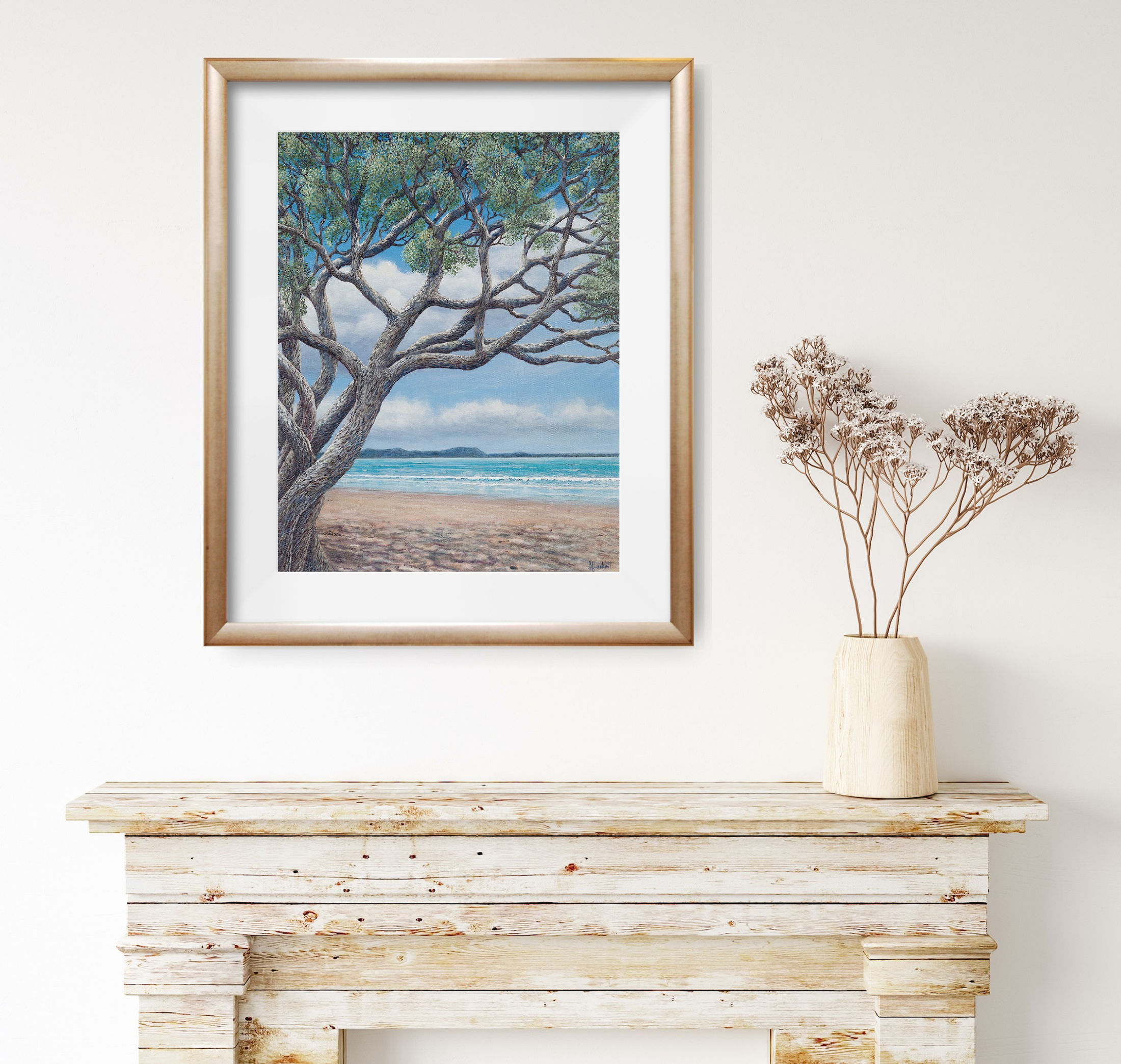 Coastal art print on wall, featuring sea, sand, and pohutukawa.