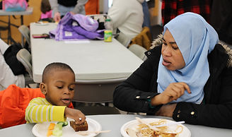 Parent and child sitting at table eating food