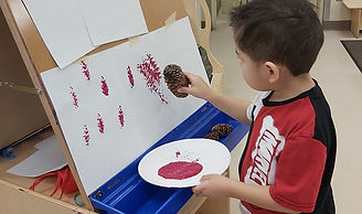 Child painting with pinecone