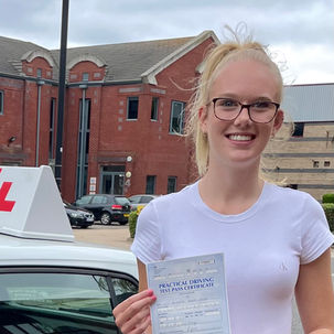 Young woman celebrates passing driving test, holding certificate and smiling.