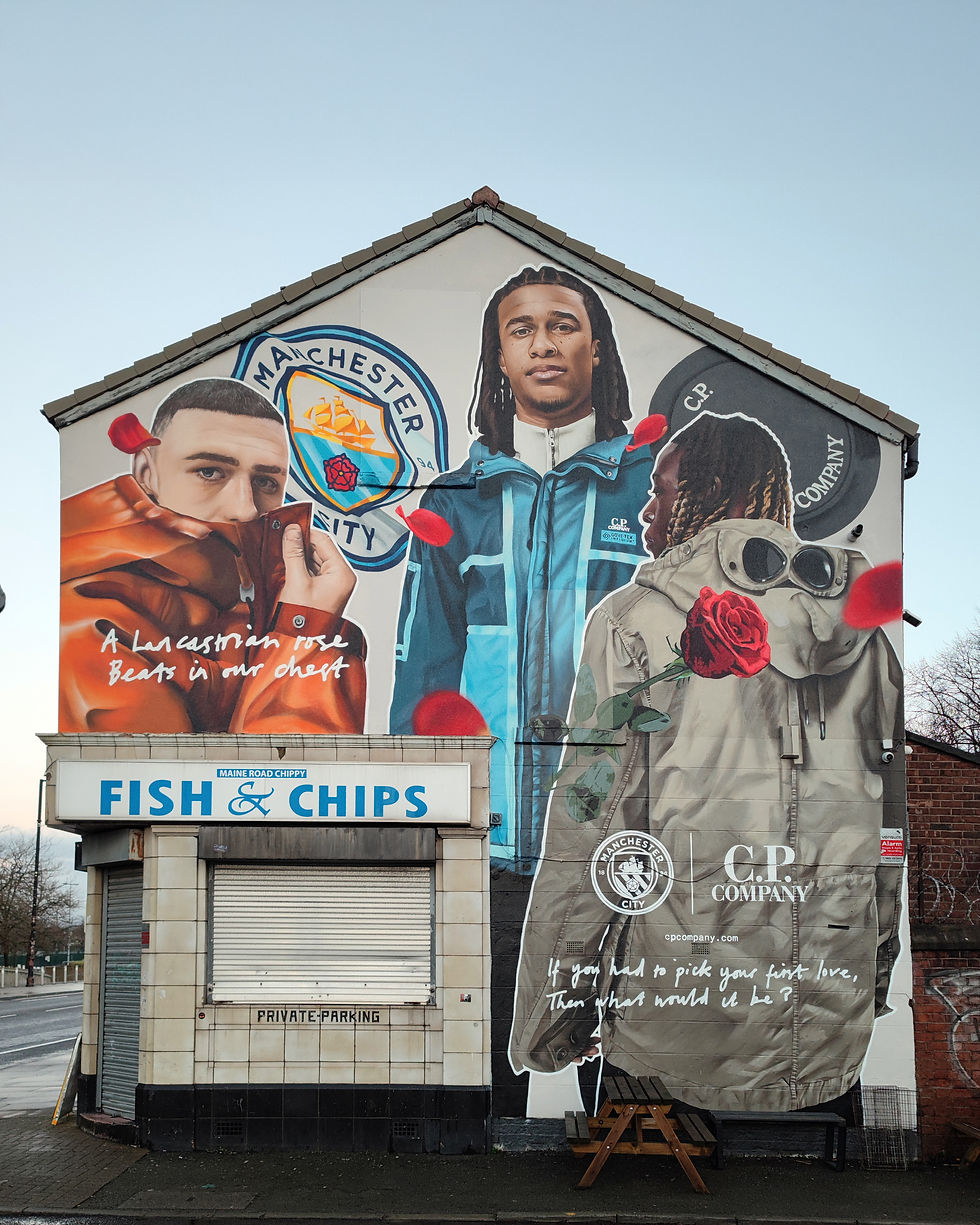 C.P. Company mural on fish & chips shop shows two men in jackets with Manchester City logo. Text reads: A Lancastrian rose beats in our chest.