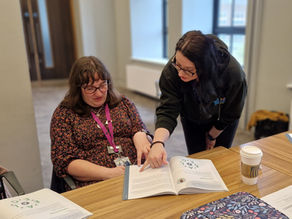 a learner is reviewing a course workbook and discusses with a member of the training team