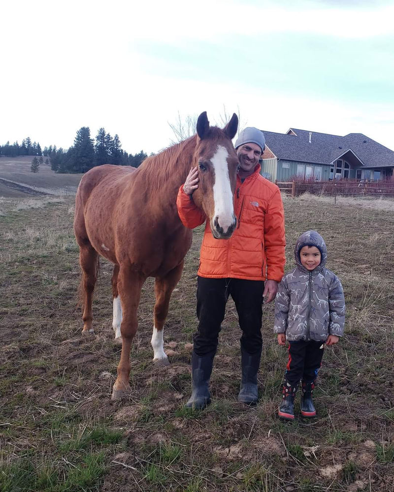Dr. Allen and his son standing with a horse on a farm call