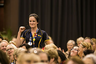 Interactor Sarah Davey from Australia at the Fighting Poverty Through Education breakout session, Rotary International Convention, 2 June 2014, Sydney, Australia. Sarah is standing with her first up in celebration while everyone around her is sitting and smiling.