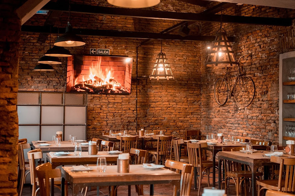 Salón del restaurante San Vicente Central con estilo rústico, paredes de ladrillo, chimenea encendida y ambiente cálido para disfrutar en San Vicente