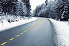 Winding asphalt road through a snowy forest