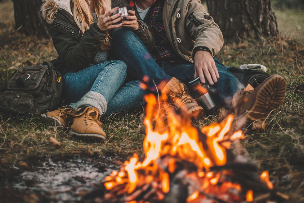 Couple warming by campfire, holding mugs
