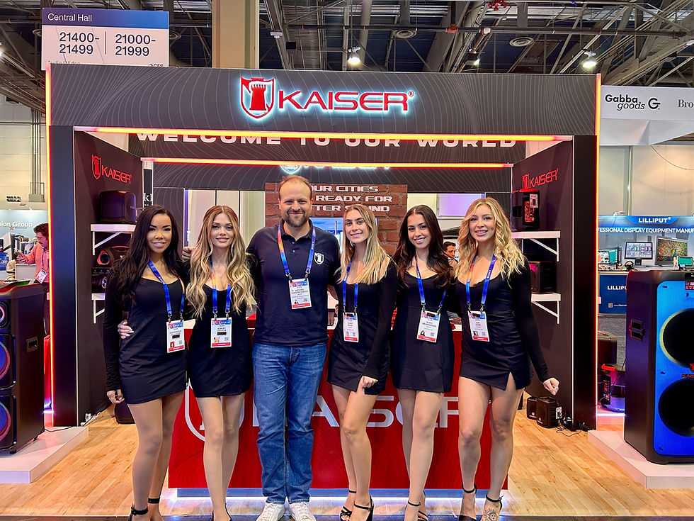 Six people pose at a KAISER trade show booth in Central Hall, with glowing red signage and a welcome banner.