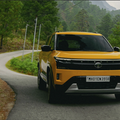 Bright yellow SUV driving on a winding road through a green, mountainous landscape.