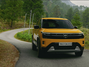 Bright yellow SUV driving on a winding road through a green, mountainous landscape.