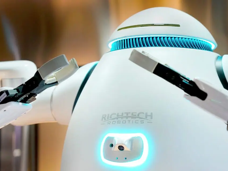 White robot with blue lights, labeled "RICHTECH ROBOTICS," stands in a metallic setting, arms raised as if in motion.