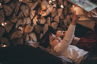 Parent and child reading a book in a cozy room