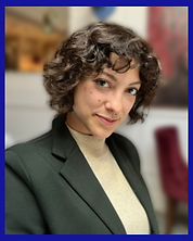 Rainbow Counsellor Chiara looks at the camera with a composed smile, wearing a green suit and brown jumper.