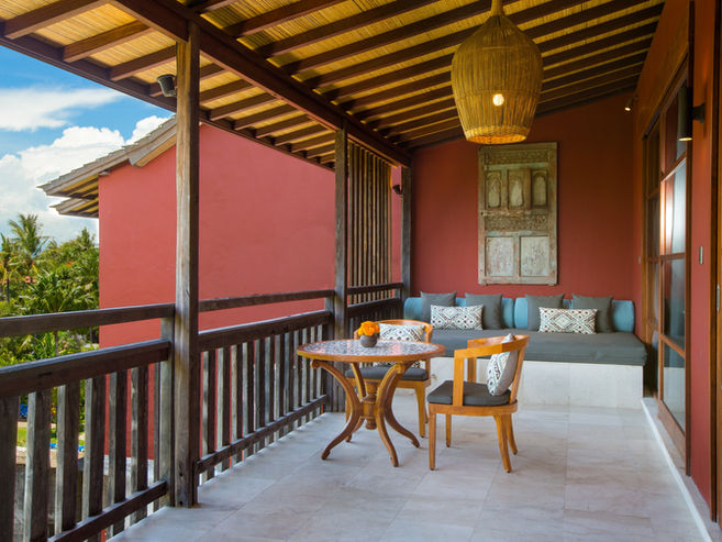 Large balcony terrace of the Amnaya Suite featuring a built-in daybed, outdoor dining table, and chairs at Amnaya Resort Kuta