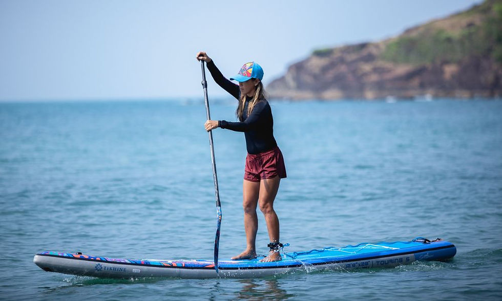 A woman enjoys a peaceful stand-up paddleboarding session on calm waters, surrounded by a stunning coastal landscape.