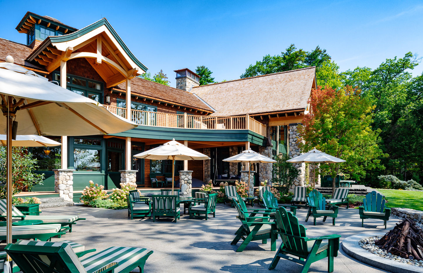 Outdoor patio with green chairs and umbrellas at a lodge.