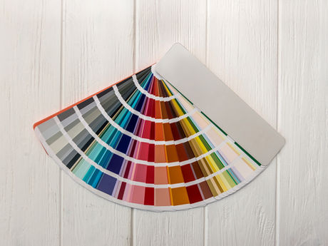 Nuancier de couleurs étalé en éventail sur un bureau en bois clair, utilisé pour l’impression et la sélection colorimétrique.