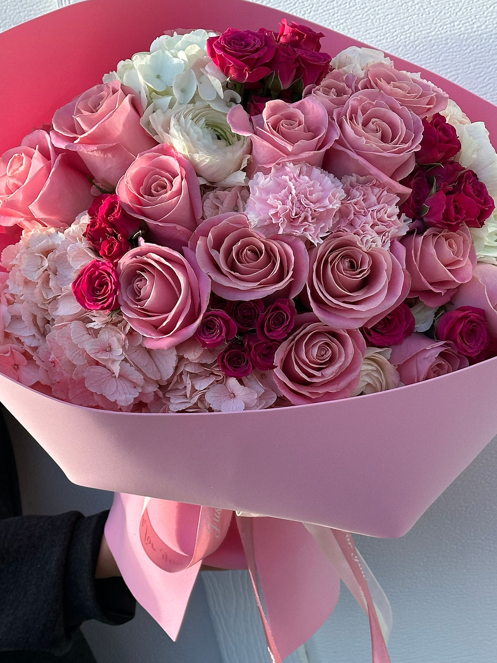 Elegant pink bouquet with roses, hydrangeas, and carnations in soft designer wrap.