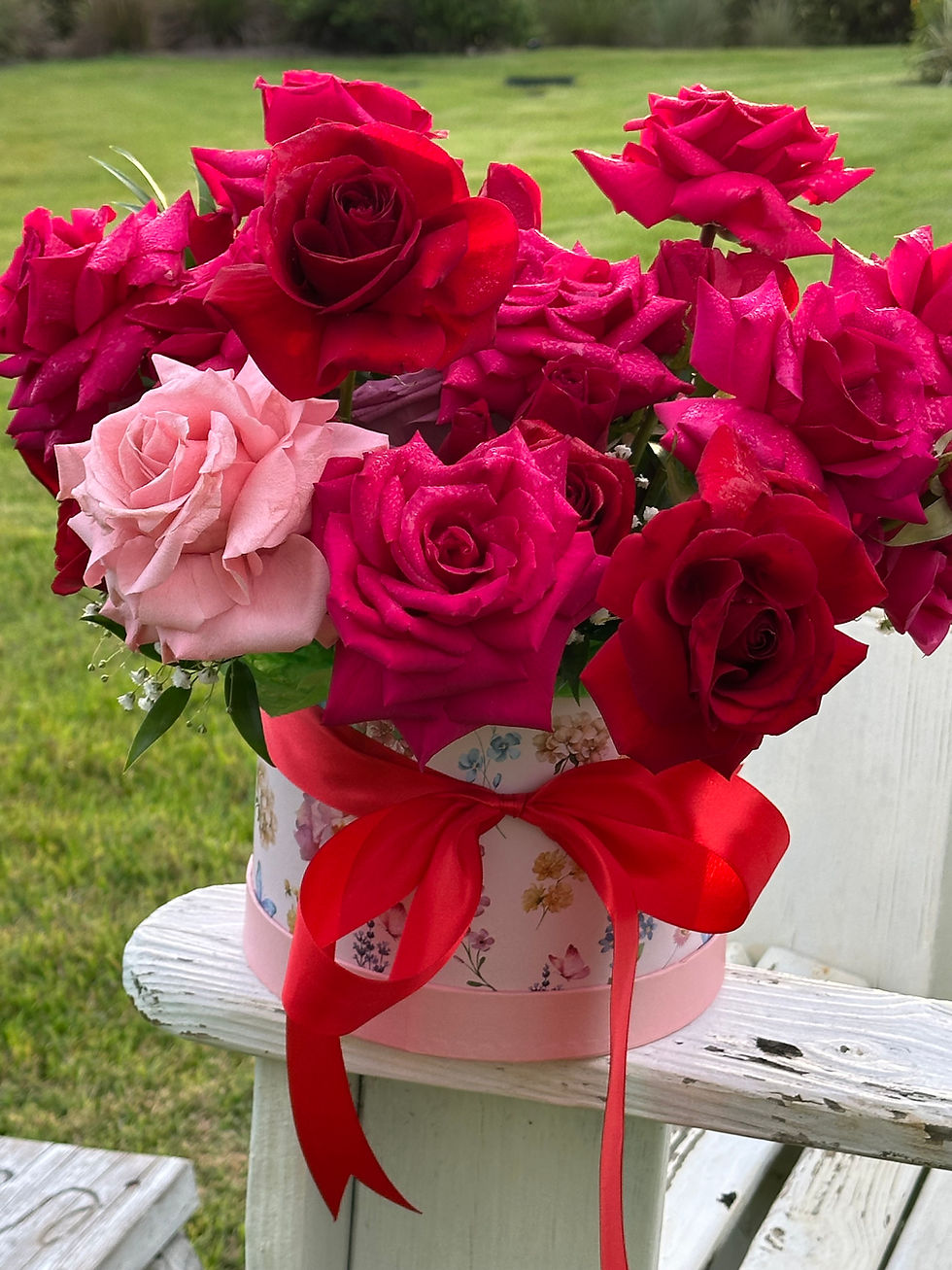 Red and pink rose bouquet in a floral hatbox with red satin ribbon.