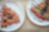 Two sweet crepes from First Round — the Strawberry Oreo Crepe and Berry Cake Crepe — plated side by side.