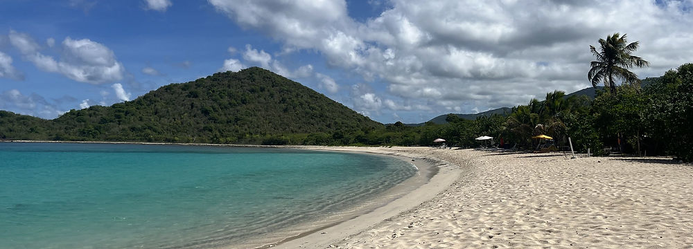 Empty white-sand secret beach curving to a green hill on a private Tortola SUV day