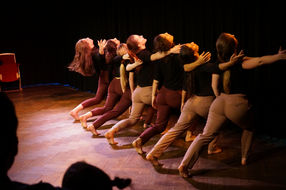Dansers in een rij, beweging, rode stoel. De performance op het podium Tamar Riani.