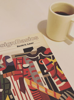 Coffee in mug and design book on a white table
