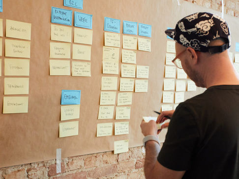 Eine Person steht vor einem Board mit vielen Post-its