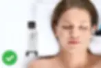 Woman receiving a facial treatment with a device, eyes closed, relaxed. White background, machine beside her, green checkmark visible.
