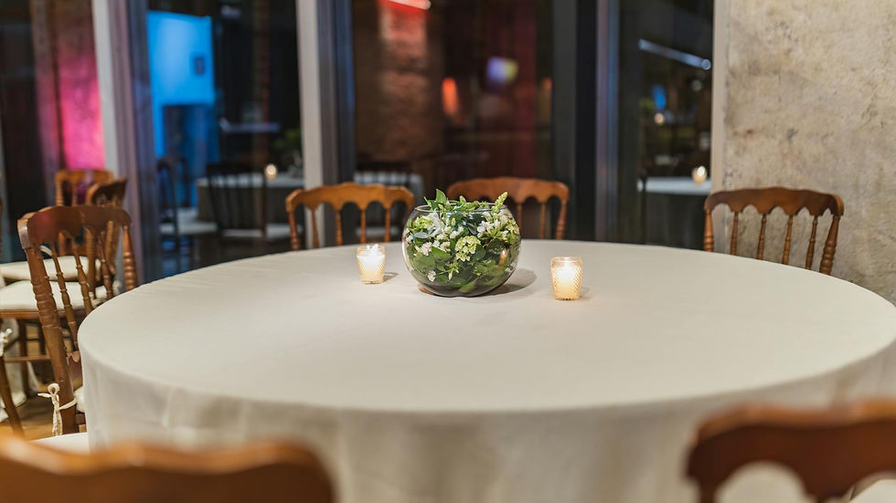 An elegant empty round table with floral centerpiece and candles in a cozy restaurant setting.