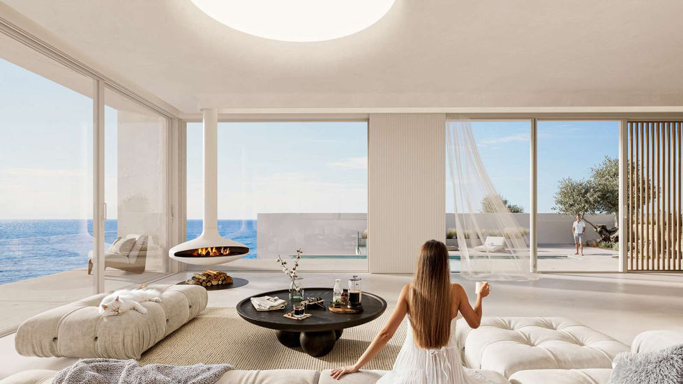 a woman sits on a couch in a living room looking out a window