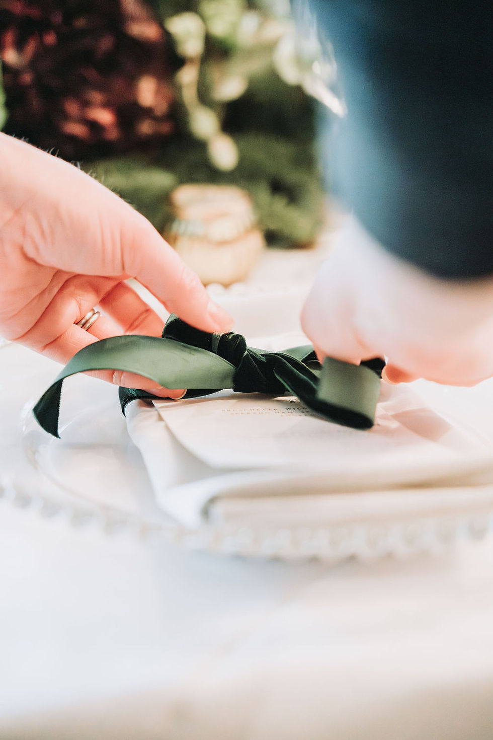 Christmas table dressed with a velvet green bow on a white napkin.