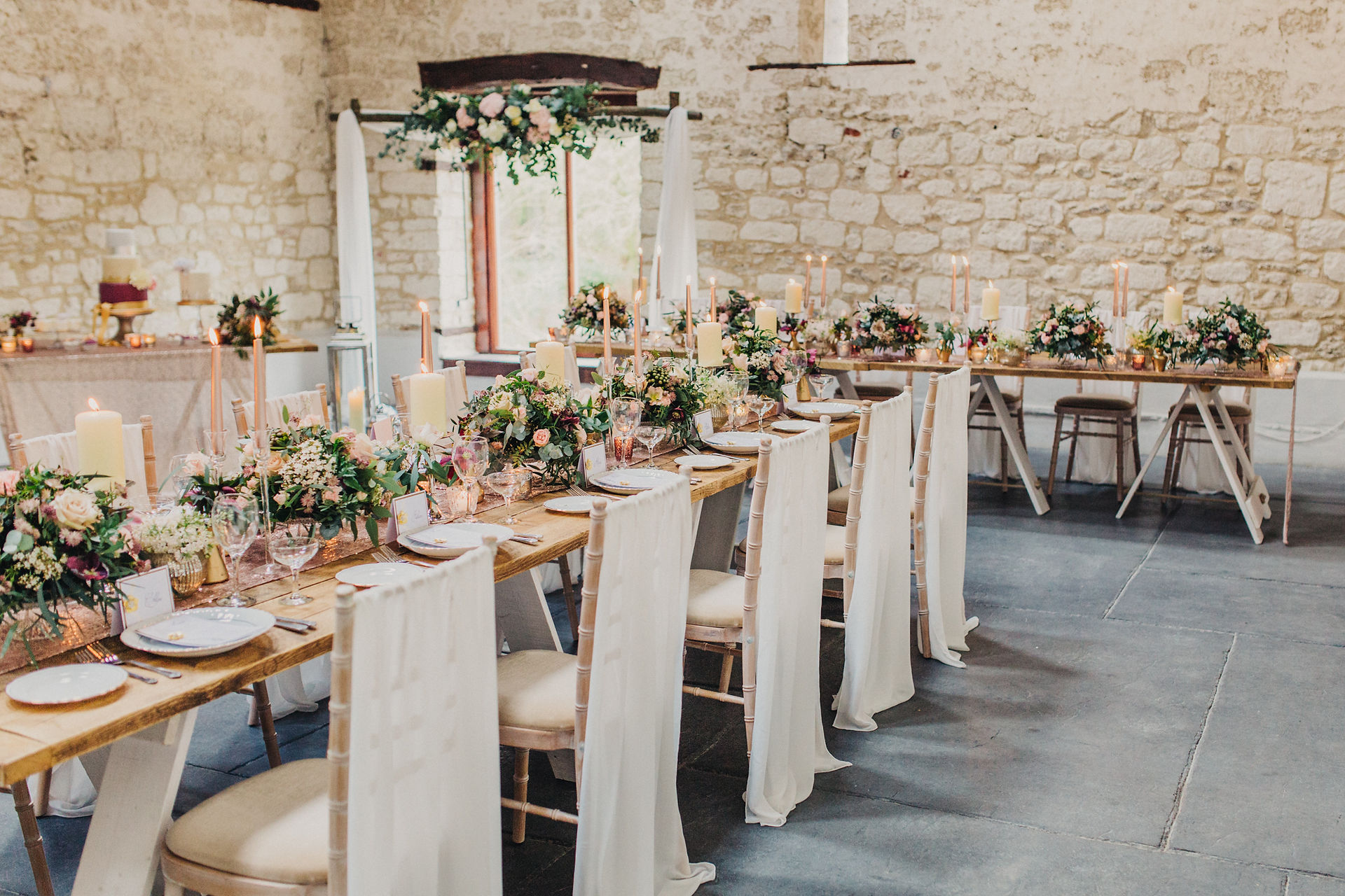 Barn venue styling in blush pink and maroon flowers with gold accessories complimented with chiffon drapes