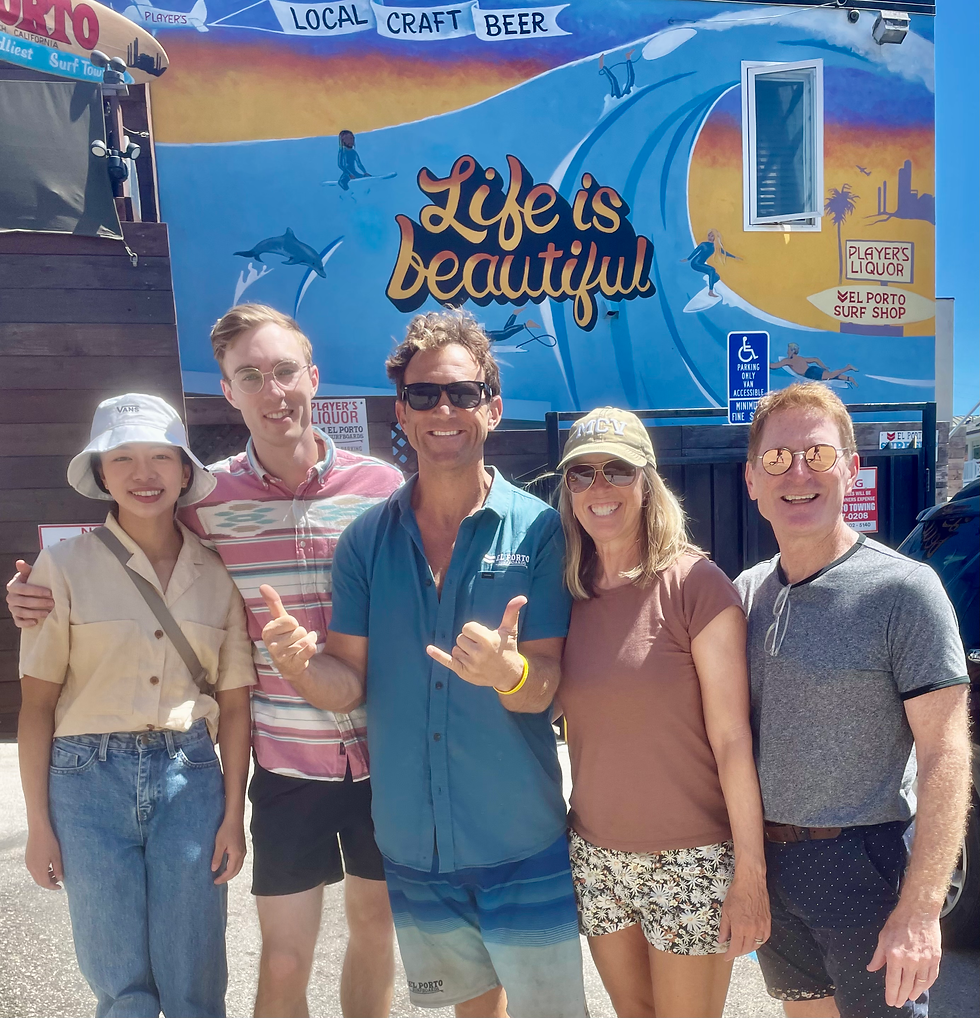 Family poses for vacation photo with surf shop owner Pack Landfair in front of "Life is beautiful" mural in El