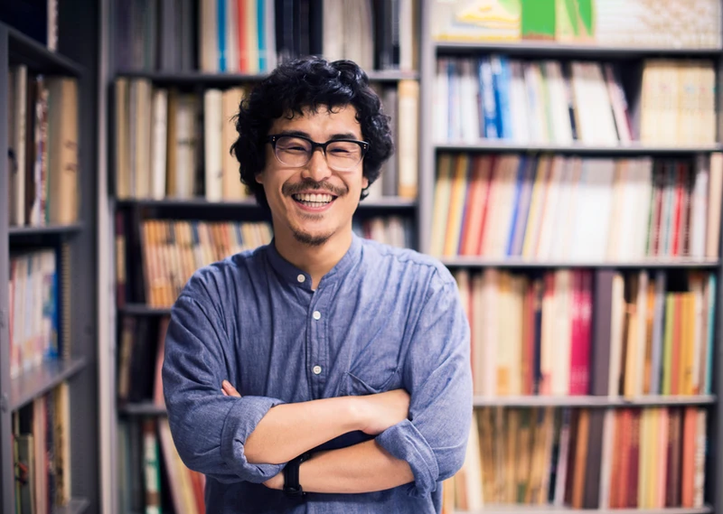 A man in a library or bookshop looking at the camera