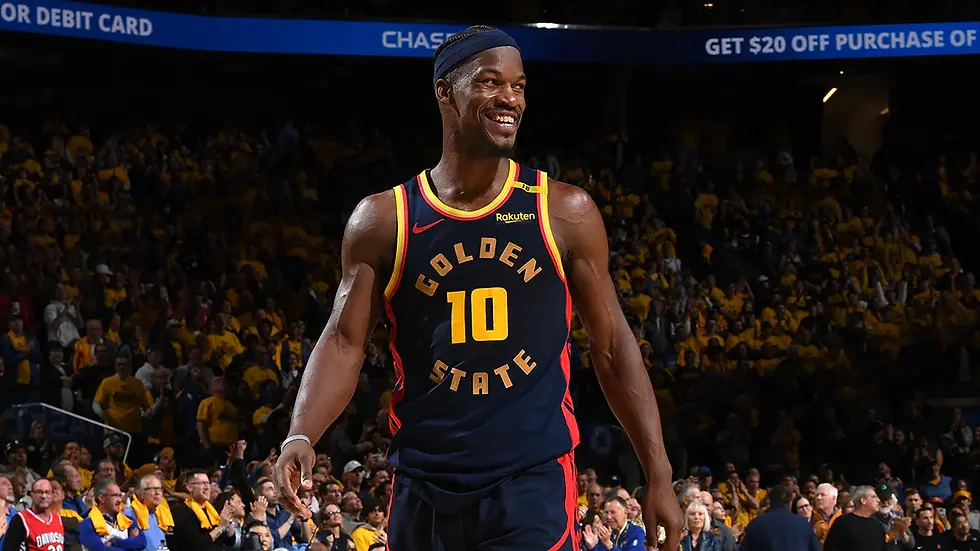 Basketball player in a "Golden State" jersey smiles on a court.