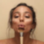 Woman blowing dust off a beauty treatment blusher brush