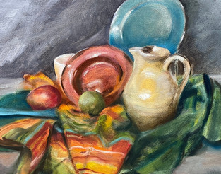 Assorted solid colored pottery grouped on a green, a teal, and a mulit-striped fabric with papayas placed in front of the vessels