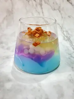 蜜豆子手搖飲原料批發供應商-杯中裝有蝶豆花果凍、芋頭布丁、冰粉、白玉珍珠、山楂碎的漸層果凍杯的漂亮食譜建議