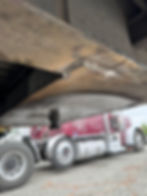 Close-up of semi-trailer kingpin with red truck behind