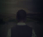 A photo of the back of a man's head with close-cut dark hair. He is looking out at a large mountain range and clear sky.