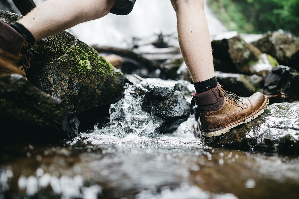 hiker crossing a stream in hiking boots