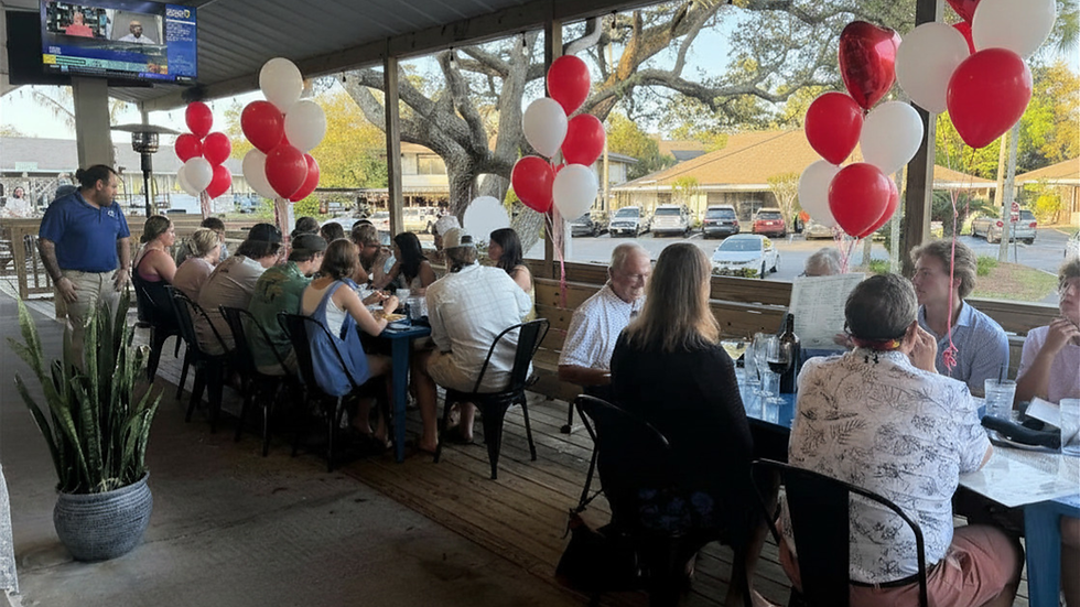 Groups of people celebrating and eating on the porch at Wolf Island Oyster Co.