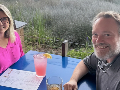 Couple enjoying drinks and dining with scenic marsh views at Wolf Island Oyster Co.