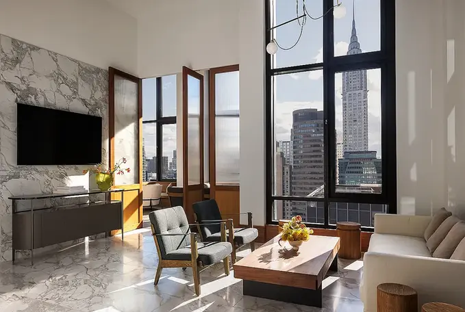 Living room with city views and large windows at 135 East 47th Street #8D apartment for rent