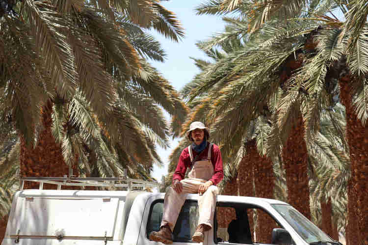 Oleh Nikita Smelyanskiy sitting on top of his white van with date palms behind him