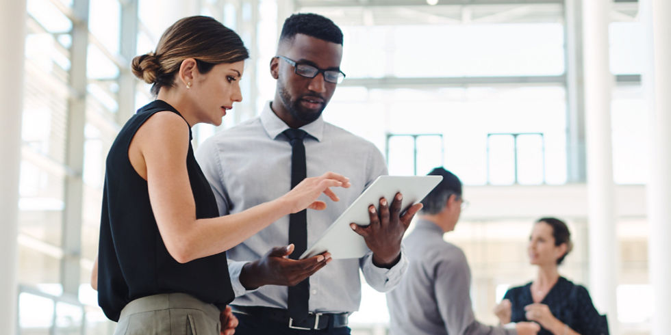 Business professionals collaborate and review information on a digital tablet in a modern office setting.