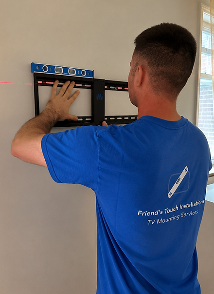 Professional TV mounting installer using a level to ensure accurate TV placement